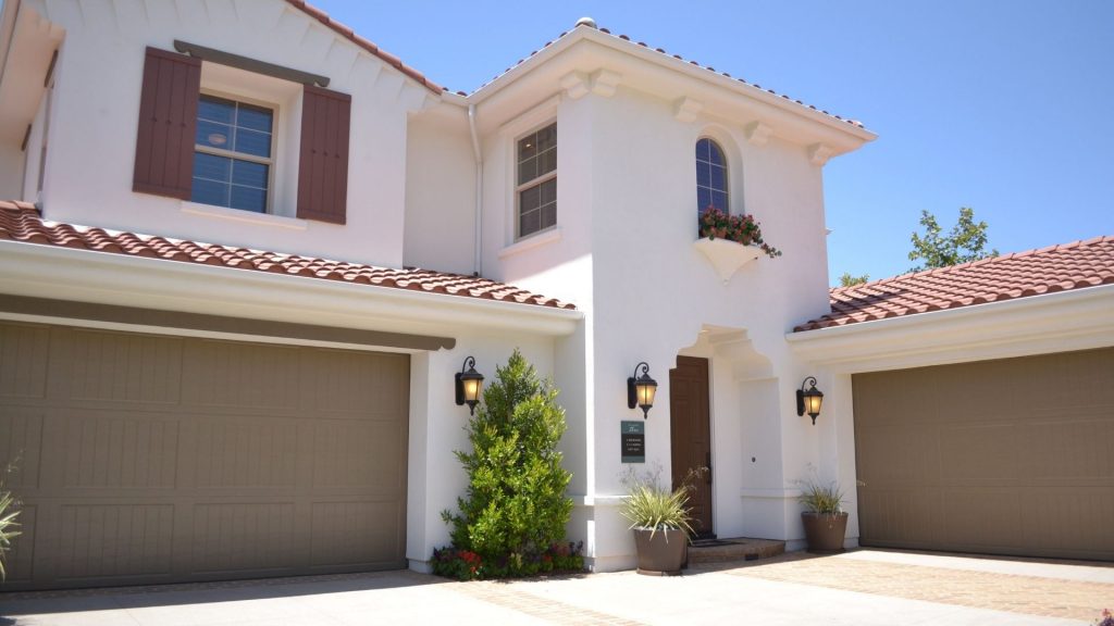 Paved driveway leading to a two-storey house with tiled roof and twin garages