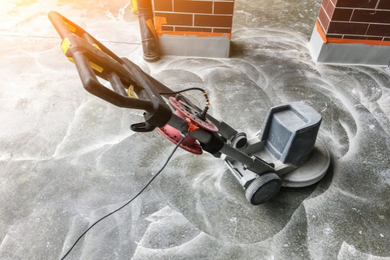 Edging grinder polishing a concrete floor next to brick support columns
