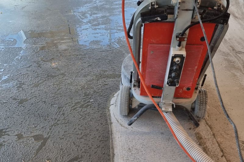 Close-up of a concrete grinding machine's control panel on a wet ground floor