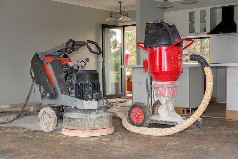 Concrete grinding machine and dust extractor set up in a home kitchen during a flooring project